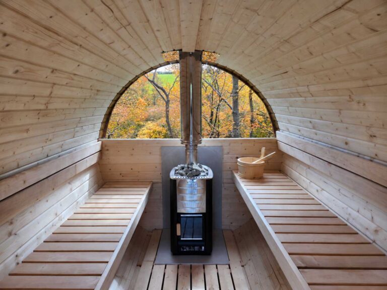 Timber sauna interior with a round window overlooking autumn woodland